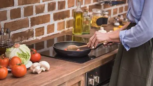 Mulher cozinhando em fogão de indução cooktop